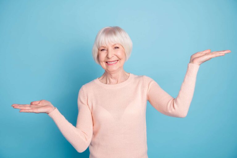 Portrait of lovely promoter holding her hands palms with beaming smile wearing pastel jumper isolated over blue background