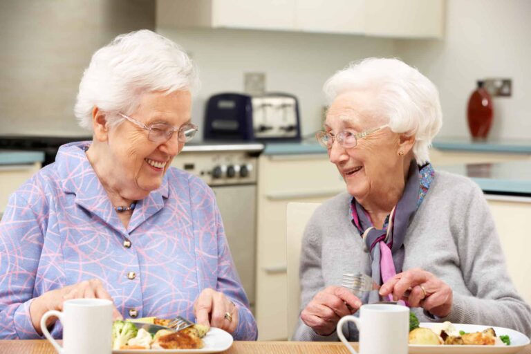 Two gray haired friends enjoying a meal together