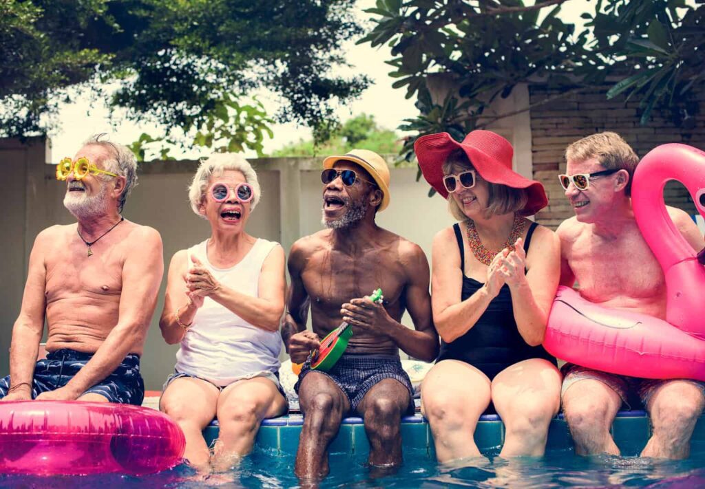 Group of diverse senior adults sitting by the pool enjoying summ