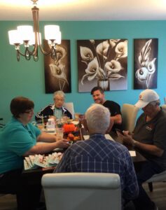 A group of seniors gathered around a table, doing a spring craft activity and laughing together